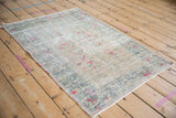 Distressed texture of vintage Oushak rug's muted ivory pile with fuchsia blossoms.
