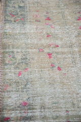 Distressed Oushak rug texture showing faded antique ivory and bright fuchsia blossoms.