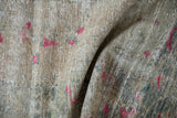 Distressed Oushak rug pile detail with fuchsia geometric blossoms, faded ivory and dusty green.
