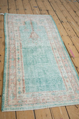 Close-up of distressed vintage Oushak runner with worn ocean green pile, visible foundation, and ivory border.