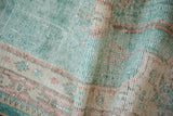 Distressed Oushak runner with bright ocean green, cream, and terracotta tones, foundation showing.
