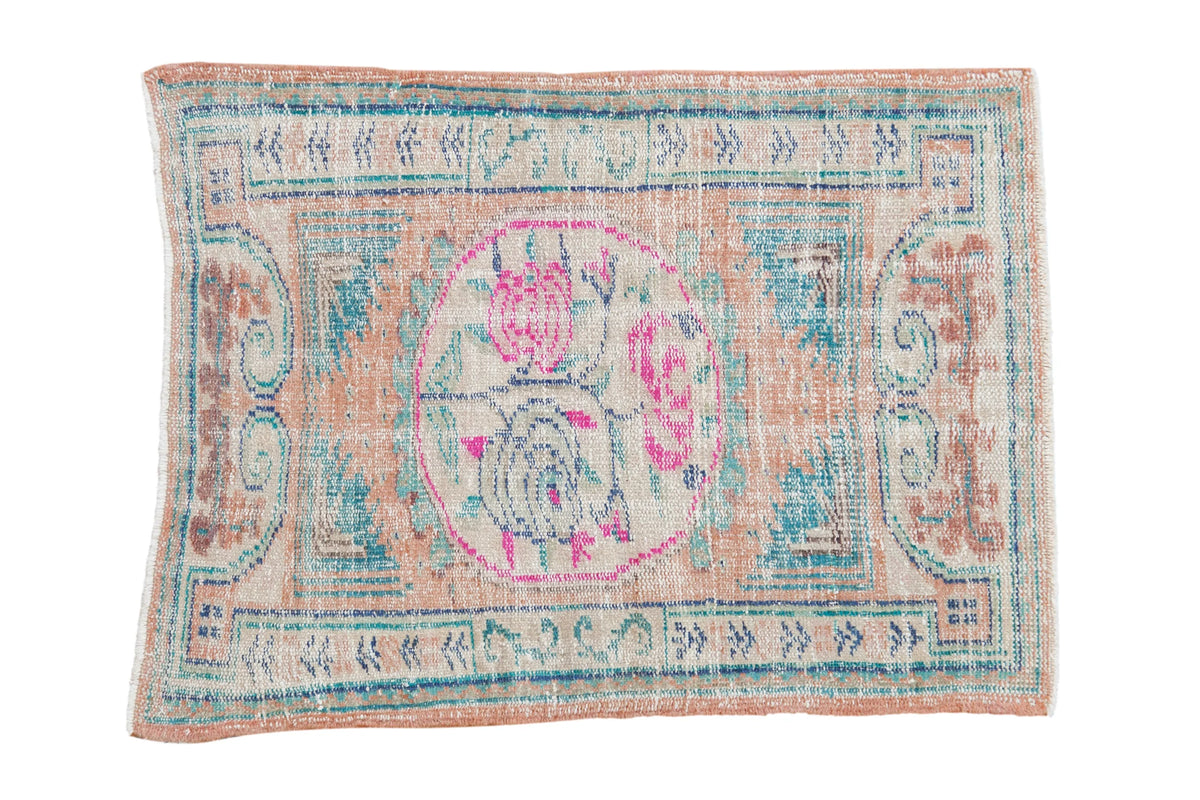 Vintage distressed Oushak rug with a fuchsia rose medallion, dusty coral field and pale turquoise accents.