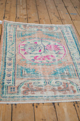 Angled view of a distressed Turkish rug's worn texture and fuchsia-accented medallion.