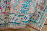 The hand-knotted texture of a distressed Oushak rug with dusty coral, turquoise, and fuchsia details.