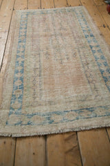 Textured distressed Oushak rug pile showing wear to foundation and faded blue border.