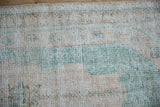 Distressed Oushak rug pile showing cream, ocean green, and pale coffee brown knot heads.