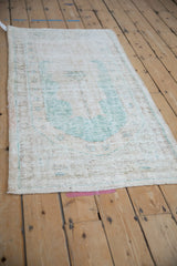 Faded ocean green prayer motif and exposed foundation on a distressed vintage Oushak rug.