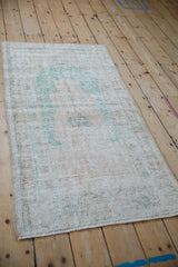 Distressed Oushak runner's decorative low pile texture, showing cream and ocean green.