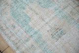 Worn, textured pile of vintage Oushak runner, showing cream, ocean green, and pale brown.