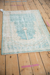 Angled, full-length view of a distressed vintage Oushak prayer rug in ocean green.