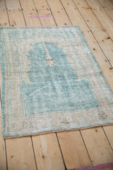 Full view of a distressed Turkish Oushak prayer rug with a heavy patina over its ocean green and cream design.