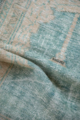 The textured, time-softened weave of a distressed Oushak rug in ocean green and cream tones.