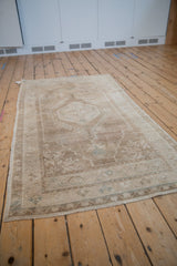 Distressed Oushak rug with faded sand, cream, and dusty slate blue hexagonal medallion.