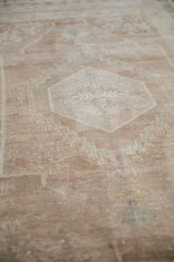Sand-toned Oushak rug's distressed texture, showing a faint hexagonal motif and visible wear.