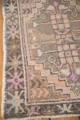 Distressed Oushak rug corner with faded floral border pattern, low pile, and intact selvage.