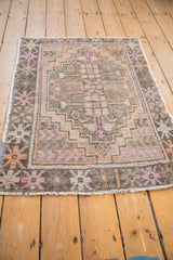 Distressed Oushak rug corner with starburst floral border, muted tangerine, and soft pink hues.