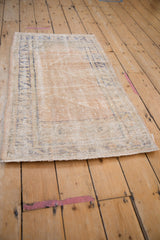Worn pale sand pile and faded blue border on the secured end of a distressed Oushak rug.