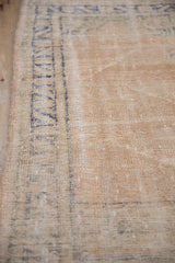 Textured pale sand field and worn cobalt blue border detail of the distressed Oushak rug.