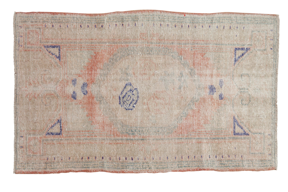 Vintage distressed Oushak rug with a roundel medallion in faded rose, seafoam, and navy on a worn ivory field.