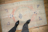 Full pattern of a distressed Oushak rug, showcasing its worn texture and soft rose and navy blue colors.