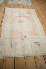Angled perspective of a vintage distressed Oushak rug, highlighting its full length and time-softened pattern.