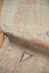 The low-pile, hand-knotted texture of a distressed Oushak rug shown on a rolled corner.
