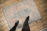 Distressed vintage Oushak rug in pale rose and ocean green with asymmetric medallion.