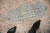 Close-up of distressed vintage Oushak rug, showing arrowed medallion end, faded pale rose and ocean green tones.