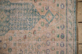 Distressed vintage Oushak rug edge: worn pale rose pile, blue-green lines, and selvage.