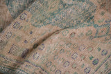 Distressed Oushak rug texture, showing worn pile, pale rose, and dusty green hues.
