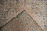 Distressed Oushak rug corner reveals worn pile, pale seed motifs, and turquoise selvedge.
