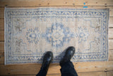 Distressed vintage Oushak runner with faded blue diamond medallion and visible foundation wear.