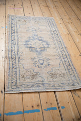 Distressed Oushak rug runner corner with dusty denim blue floral motifs and intact selvage.