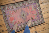 Expertly restored corner of distressed Oushak rug, with pink, purple, and green patterns.