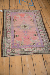Distressed Oushak rug featuring an abrashed pink field, purple medallion, and serrated vine border.