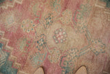 Decorative distressed Oushak rug detail: faded pink, dusty turquoise, beige floral motifs.