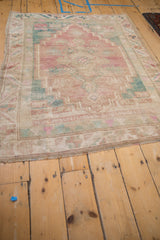 Distressed Oushak rug close-up showing worn pile texture in pink, beige, and seafoam green.