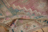 Distressed vintage Oushak rug's worn hand-knotted pile showcasing soft pink and seafoam green.