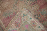 Distressed Oushak rug showing its soft pink and turquoise pile with visible hand knotted foundation.
