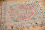 Distressed pink, turquoise, and beige geometric border on a vintage Oushak rug.
