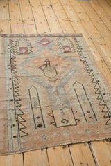 Distressed edge of a vintage Oushak rug with muted cantaloupe and soft slate blue tones.