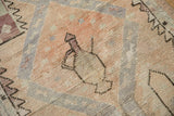 Distressed Oushak rug detail: geometric handled jug motif in soft cantaloupe and aubergine.