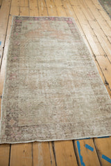 Distressed vintage Oushak runner's textured pile, exposed foundation, and soft pink border motifs.