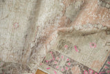 Decorative distressed pile of an Oushak rug, highlighting bubblegum pink motifs and antique ivory tones.