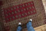 Vintage Anatolian rug showing repeating raspberry red gul motifs, intricate geometric borders, and textured pile.
