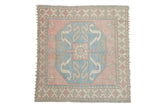 Distressed vintage Oushak square carpet with pale pink and light blue octagonal medallion.