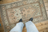 A person's perspective looking down at a vintage distressed Oushak rug with a prayer design.