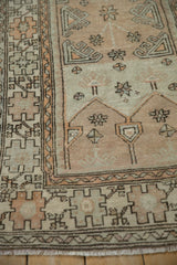 Distressed pile on a vintage Oushak rug showing starburst floral and prayer motifs.