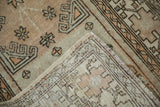 Corner of the distressed Oushak rug folded over to show the hand-knotted foundation and secured edge.