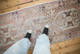 Vintage distressed Oushak runner showcasing muted coral and blue geometric design, worn pile.